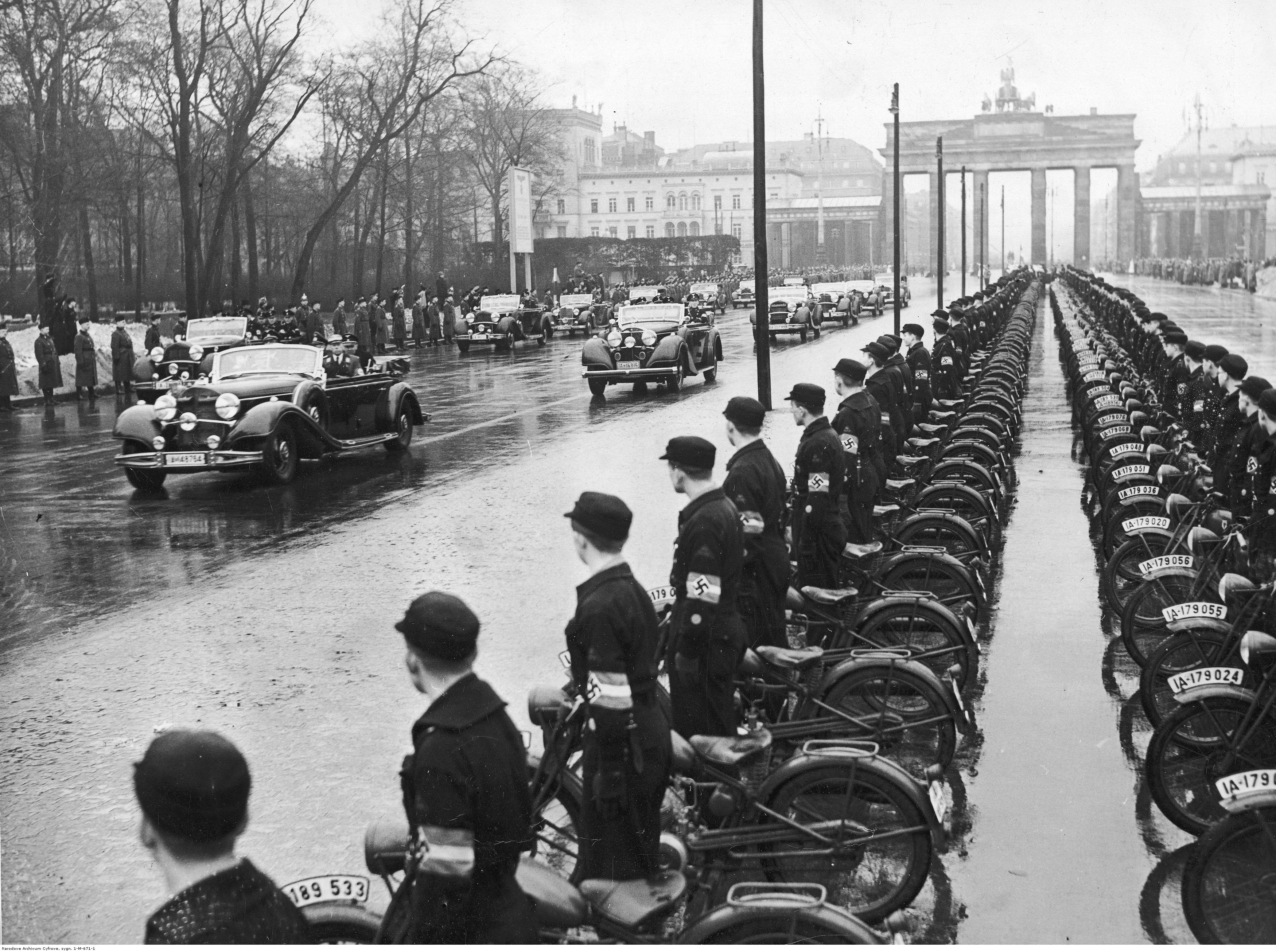 Adolf Hitler arrives at the international automobile show in front of the Brandeburg gate in Berlin, along a parade of 20000 NSKK members